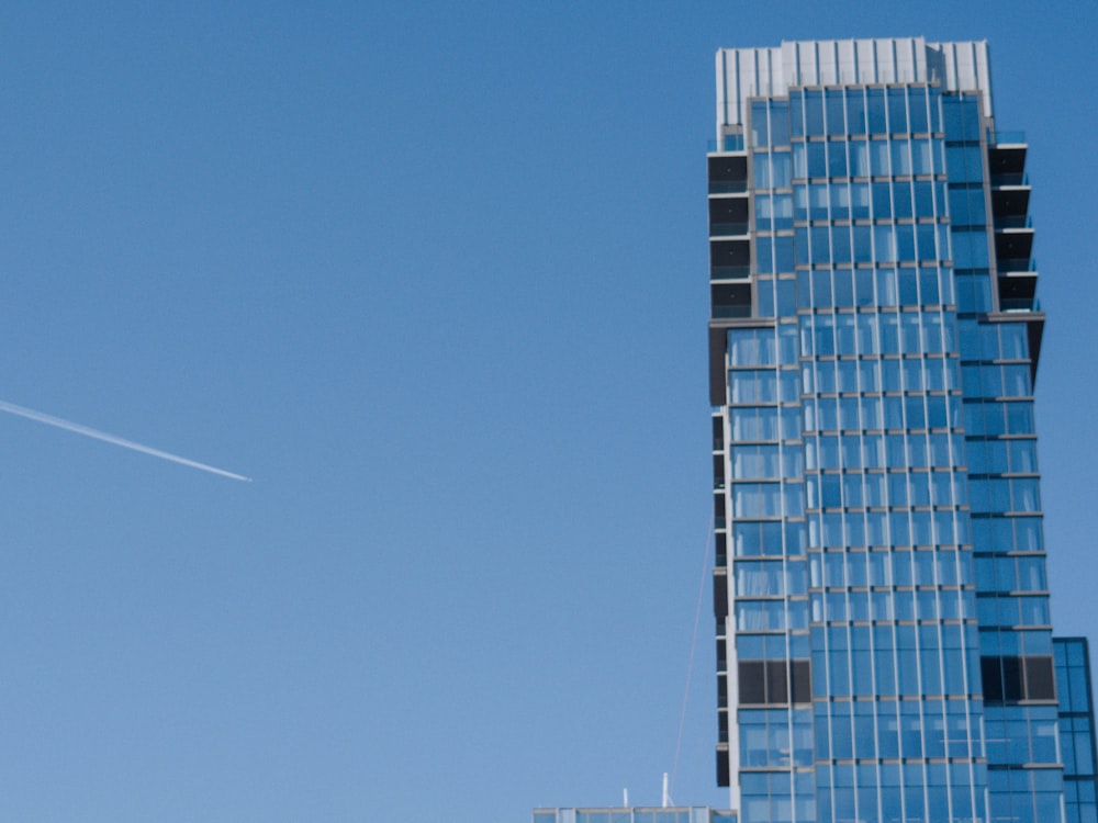 a plane flying in the sky near a tall building