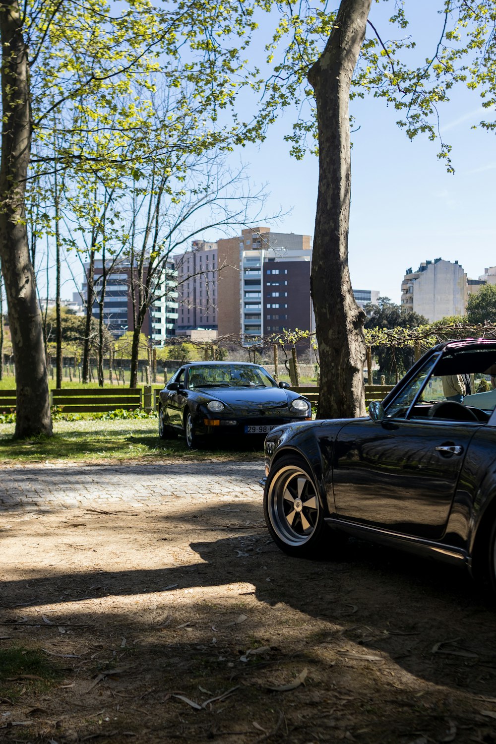 a black car parked next to a couple of trees