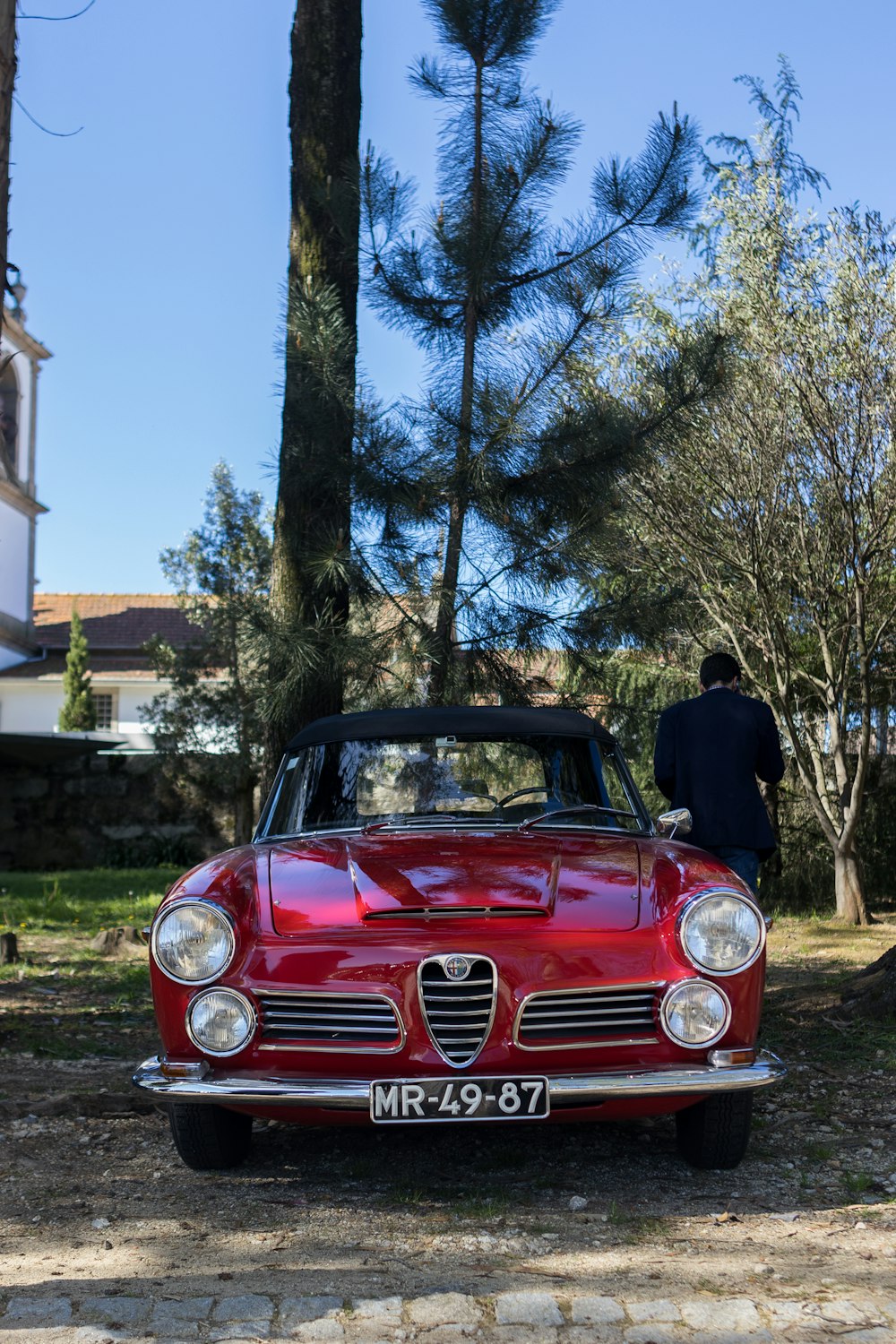 a red car parked in front of a tree