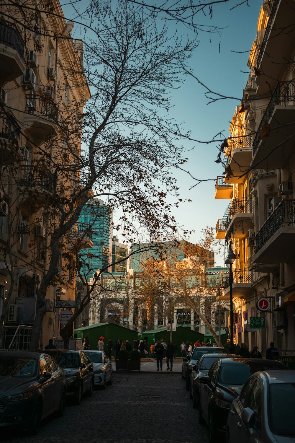 a city street lined with parked cars and tall buildings