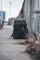 Close-up of a sleek, modern backpack resting on a concrete ledge with city skyscrapers blurred in the background.
