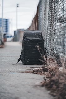 Close-up of a sleek, black Urbancarry backpack resting on a city bench with blurred urban skyline in the background.