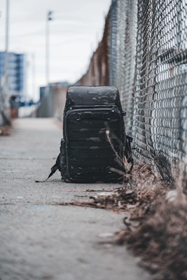 A stylish backpack casually placed on a city sidewalk with blurred urban background.