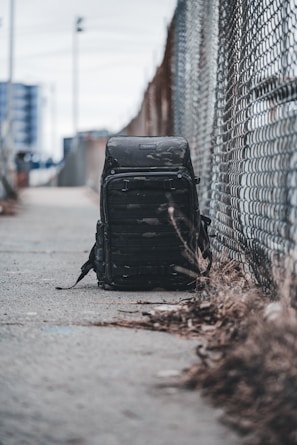 Close-up of a sleek, modern backpack resting on a concrete ledge with city skyscrapers blurred in the background.