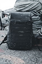 A rugged secure backpack resting on a construction site with tools visible inside.