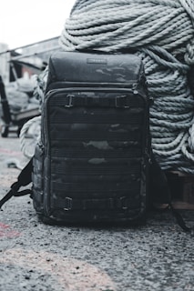 A stylish backpack and matching accessories laid out on a concrete bench with graffiti art in the background.