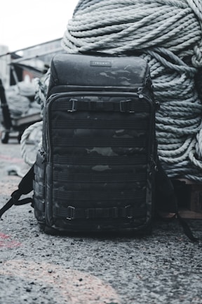Close-up of a rugged Alpha Drive tactical backpack resting on a dark steel surface.