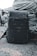 A dark camouflage-patterned backpack is placed on a rough concrete surface, with large coiled ropes stacked in the background. The setting appears industrial and utilitarian, with muted colors and textures that convey a sense of ruggedness.