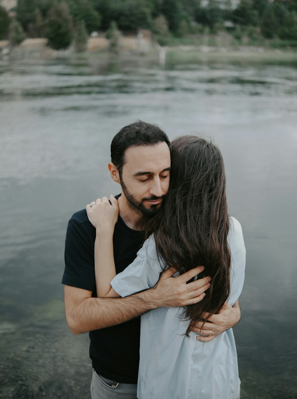 a man and a woman hugging by the water