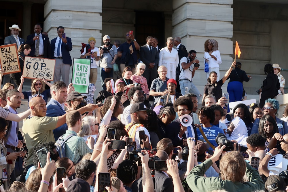 a crowd of people holding up signs in front of a building