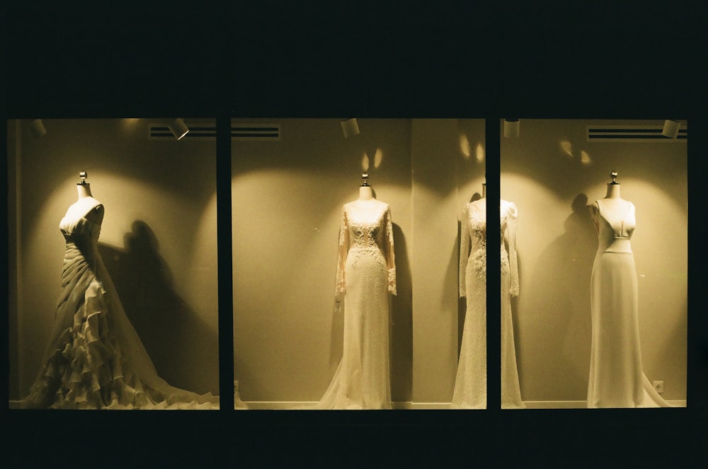 three mannequins in a window display with dresses on display