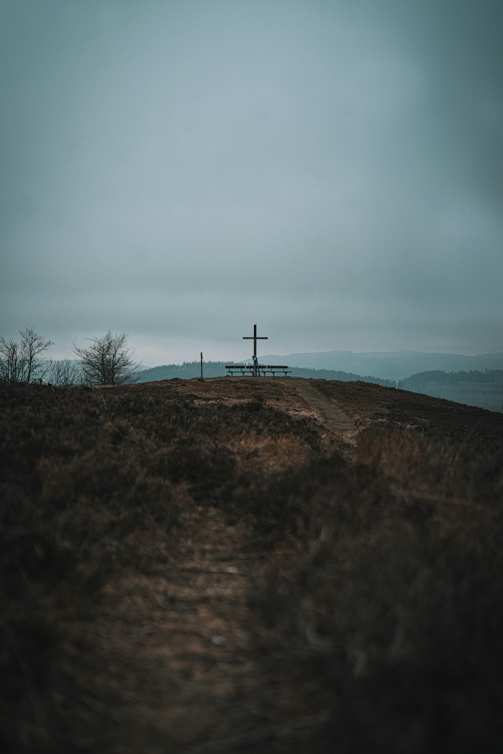 a cross on top of a hill on a cloudy day