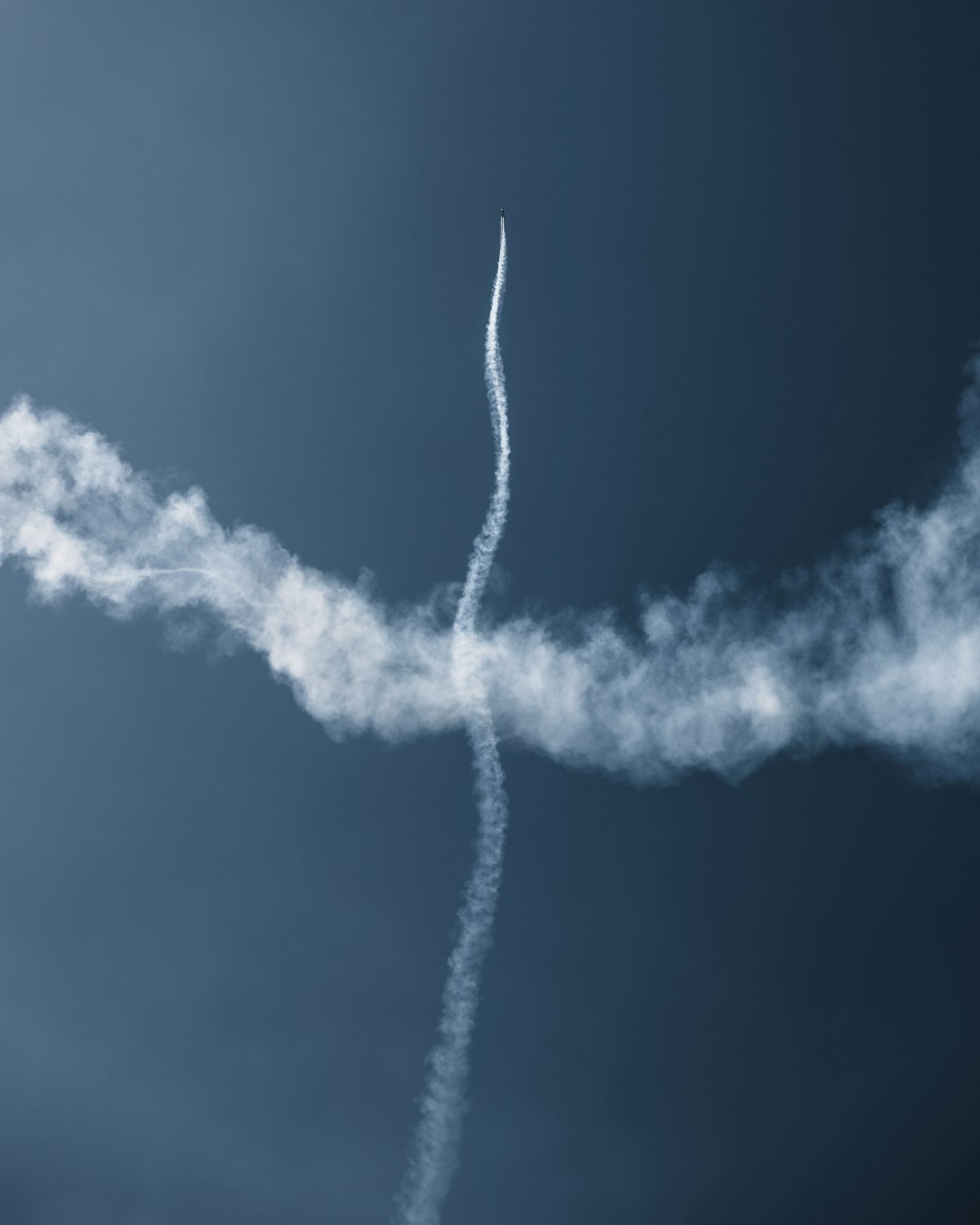 um avião voando no céu deixando um rastro de fumaça