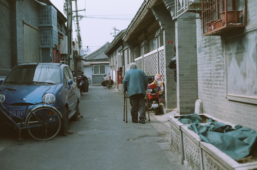 a man walking down a street next to parked cars