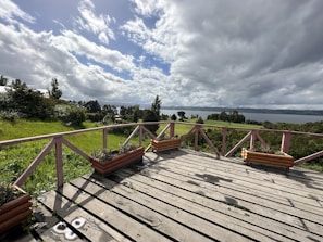 A sturdy wooden deck overlooking a landscaped backyard under clear skies.