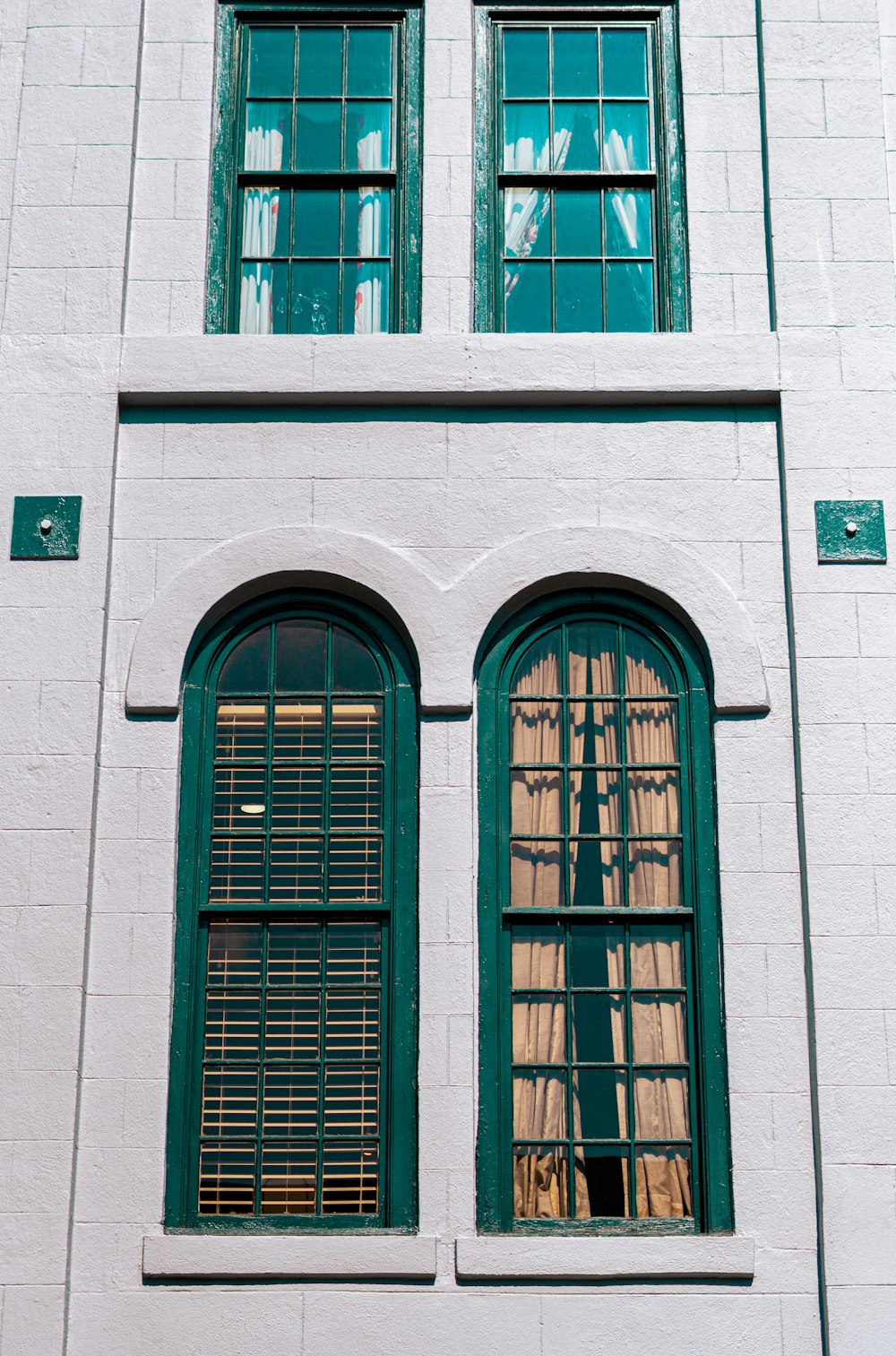 a white building with two green windows and a clock