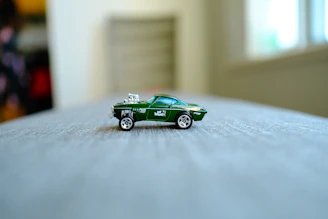 a green toy car sitting on top of a bed