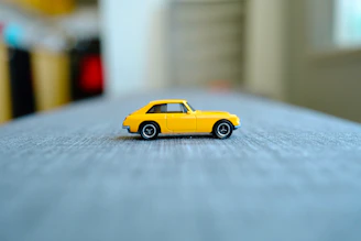 a yellow toy car sitting on top of a bed