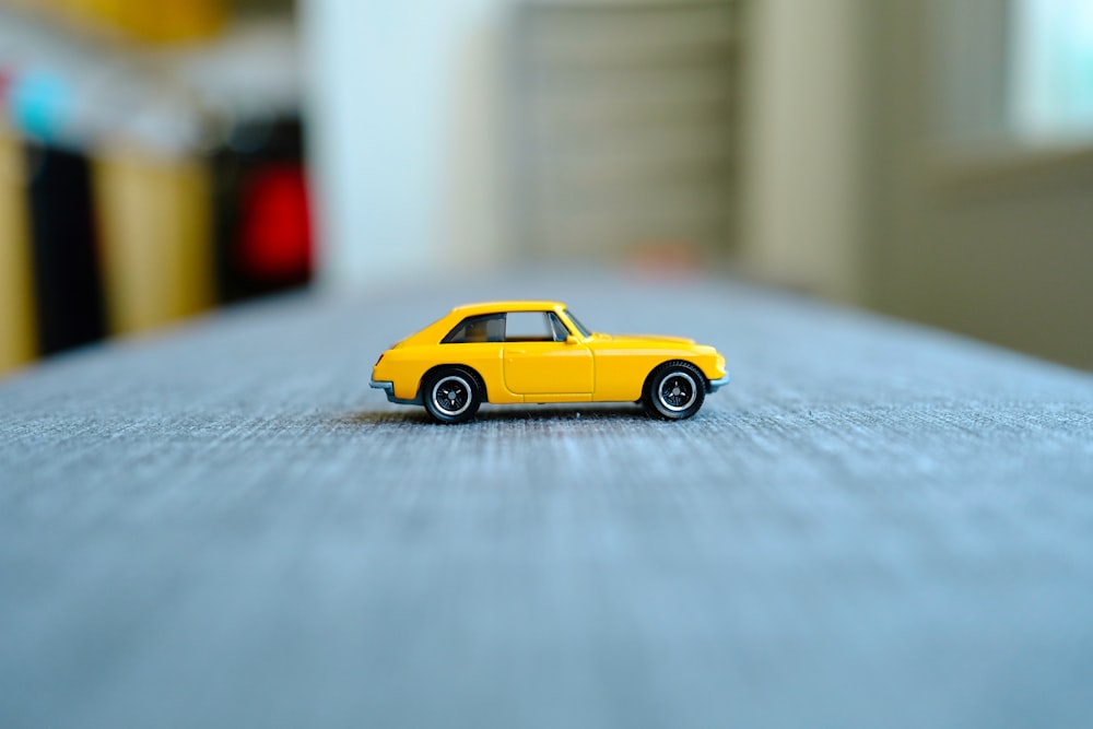 Un coche de juguete amarillo sentado encima de una cama