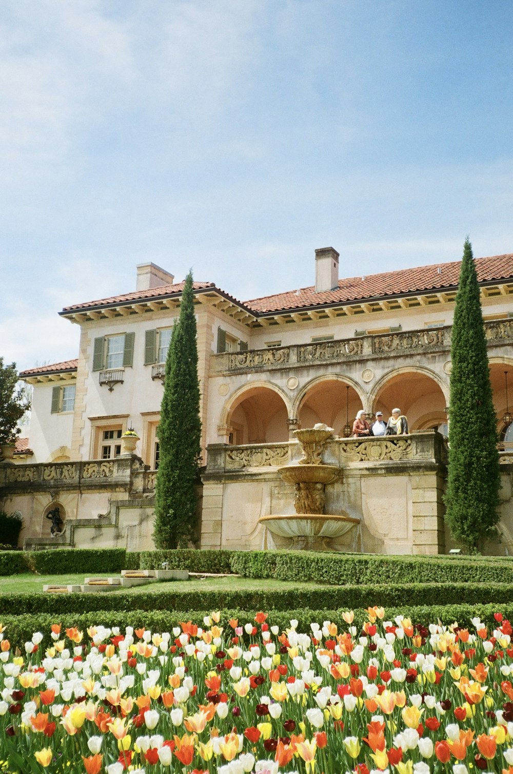 a large building with a fountain surrounded by flowers