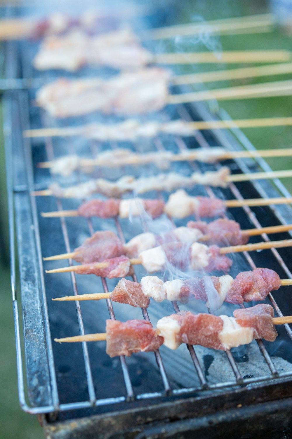 several skewers of meat cooking on a grill