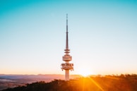A panoramic view of a completed communication tower standing tall over a rural landscape at sunset.