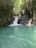A serene natural pool with cascading waterfalls surrounded by green foliage.