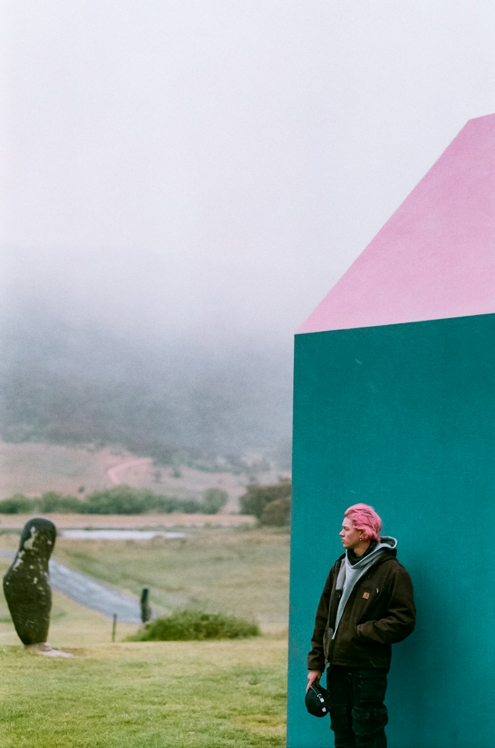a man standing next to a blue and pink structure