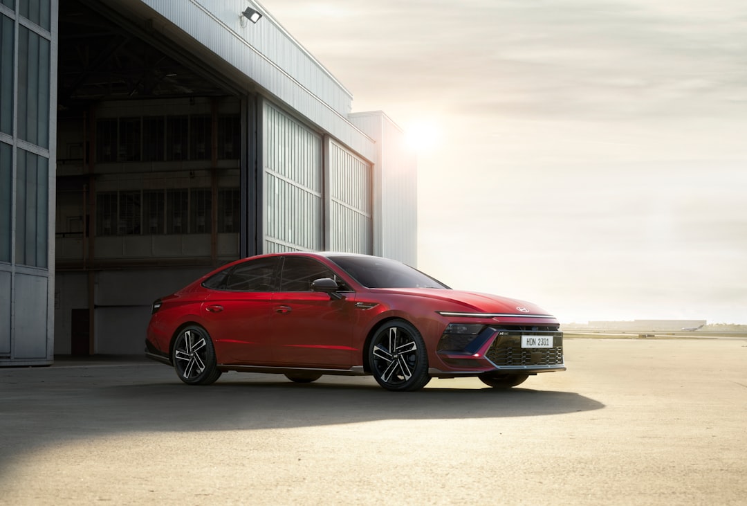 a red car parked in front of a building, The HYUNDAI SONATA in front of a warehouse