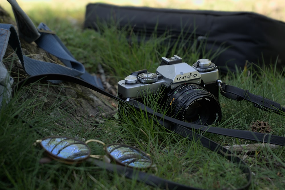 uma câmera e um par de óculos de sol deitados na grama