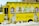 A bright yellow ice cream truck adorned with images of soft-serve ice cream cones featuring different flavors. The truck is parked amidst snow, and there are large illustrations of swirled ice cream cones in white, green, and brown colors on its sides. Menu boards with text and images of ice cream are mounted on the sides of the truck.
