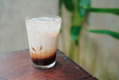 a tall glass filled with liquid sitting on top of a wooden table