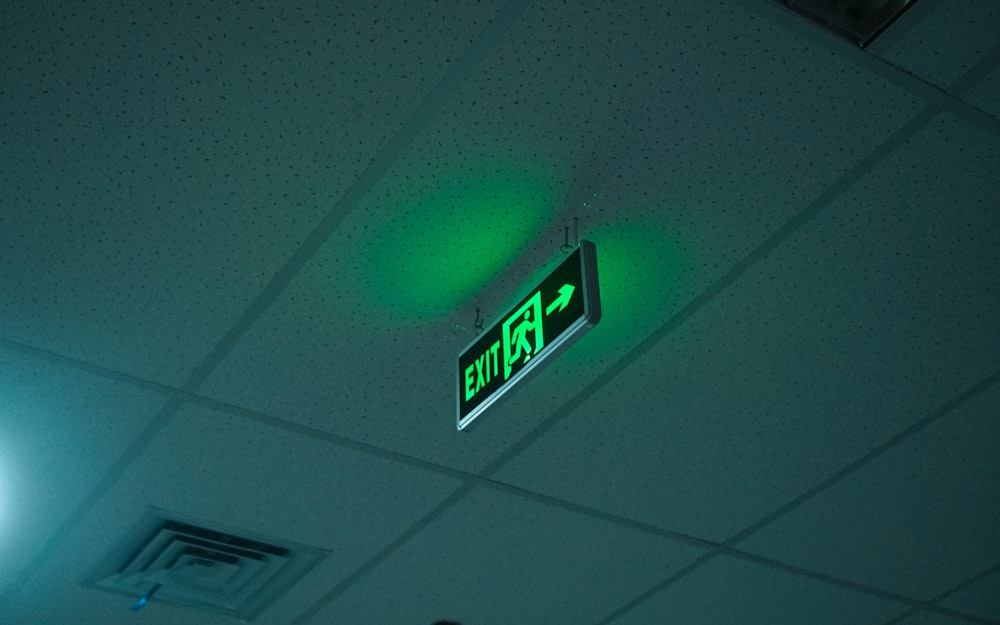 a green exit sign hanging from the ceiling