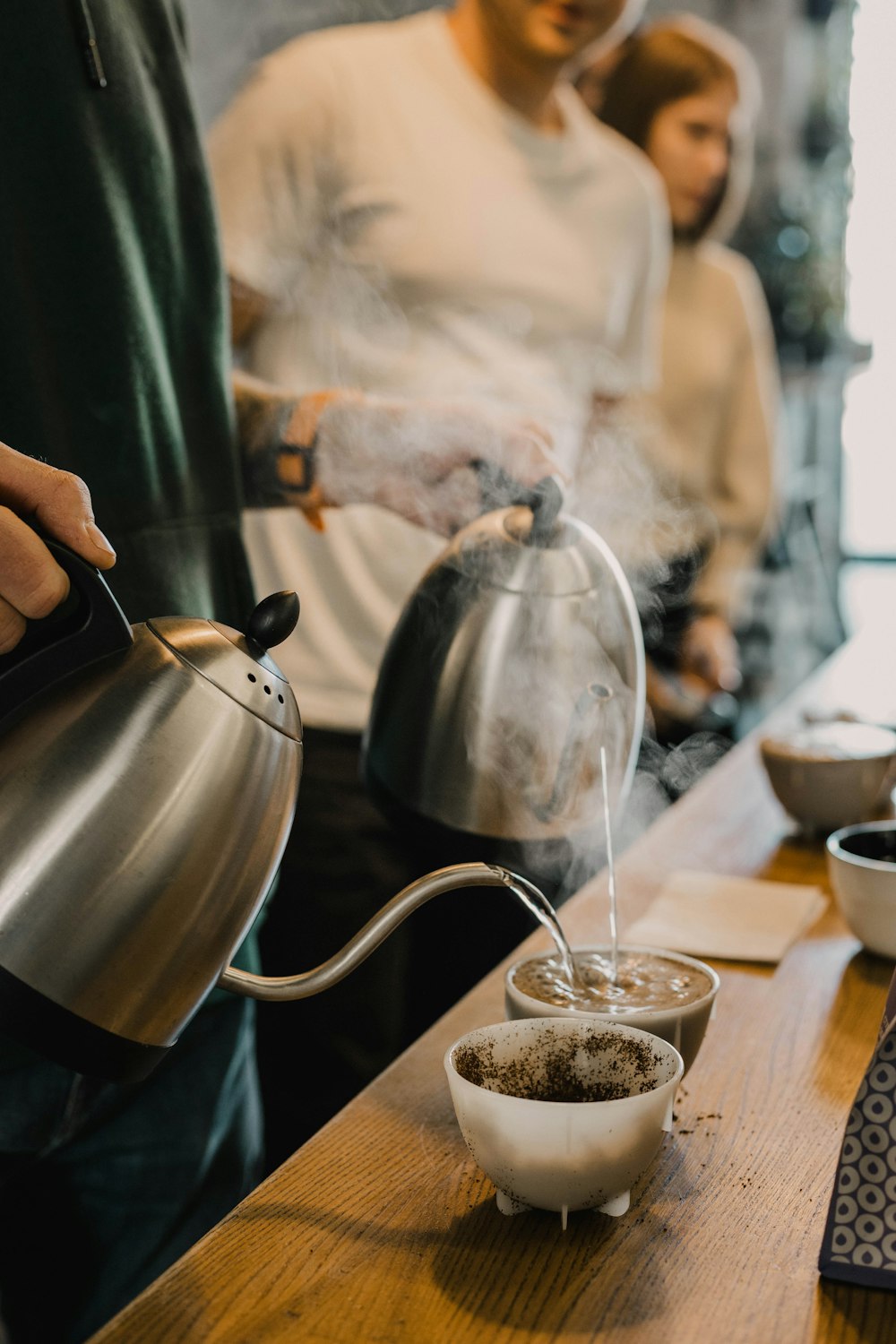 a man pours a cup of coffee from a tea kettle