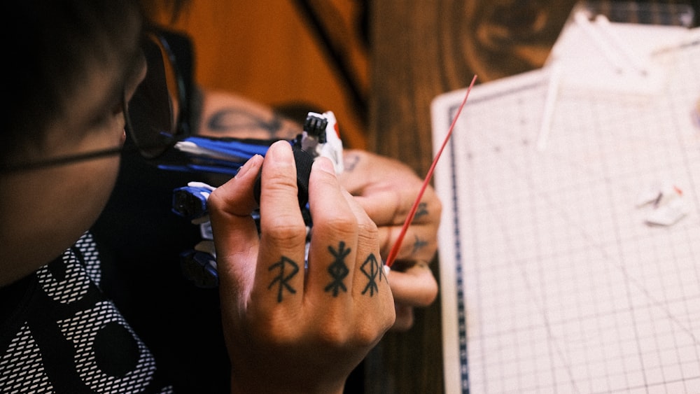 a person with a tattoo on their hand writing on a piece of paper