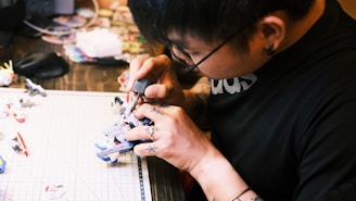 Close-up of hands assembling detailed miniature models on a workspace.