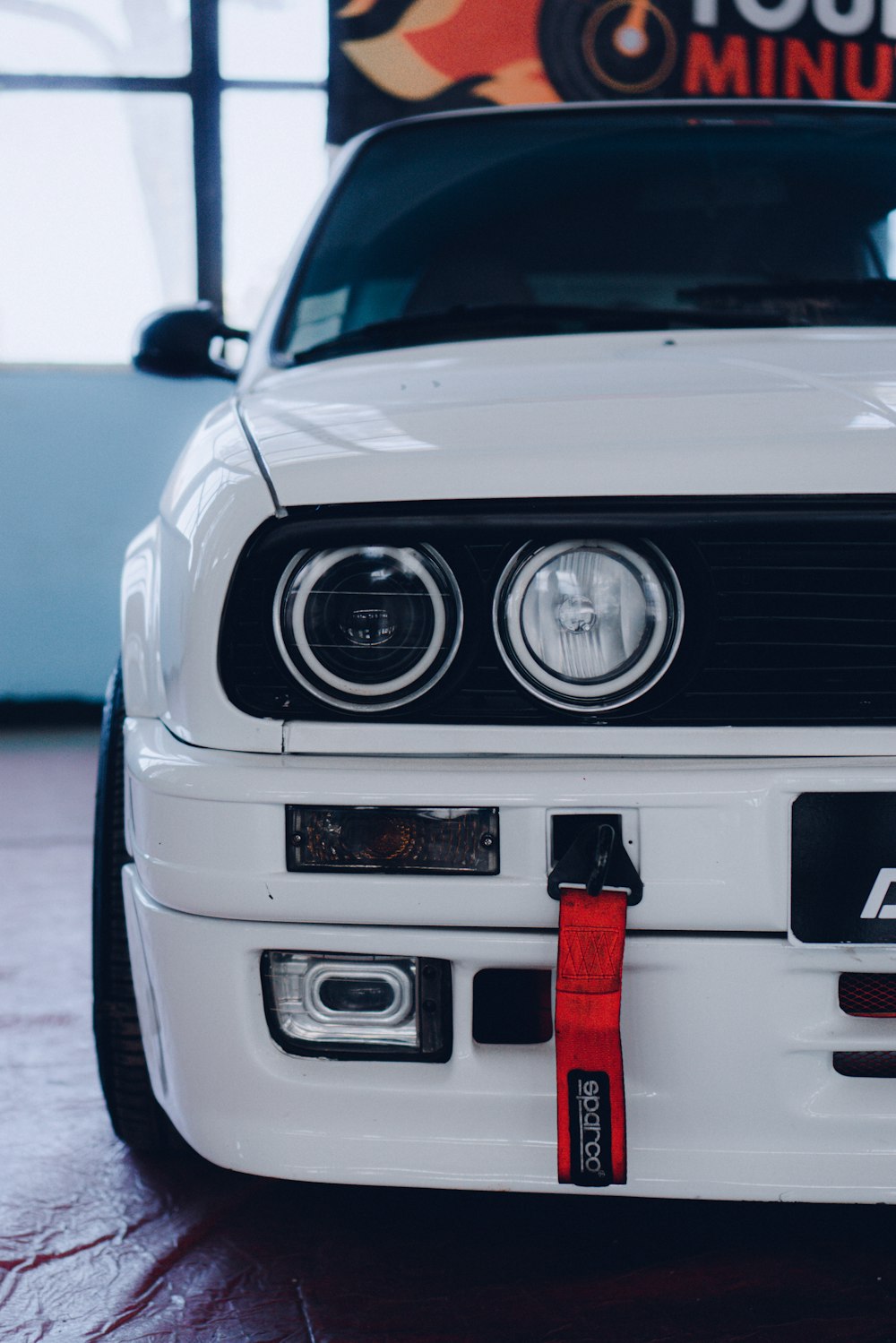 the front of a white car with a red tag on it