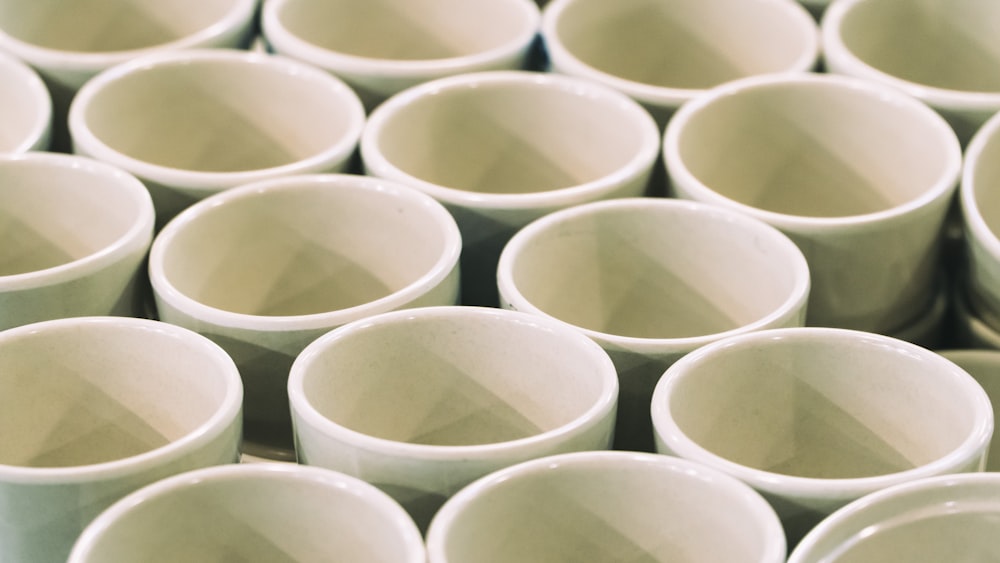 a large group of white cups sitting on top of each other