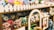 A shelf filled with a variety of plush toys in different colors and designs. The toys are arranged neatly with a decorative white picket fence on top of the shelf. Among the toys are animals with big eyes, including different creatures such as cats and rabbits.