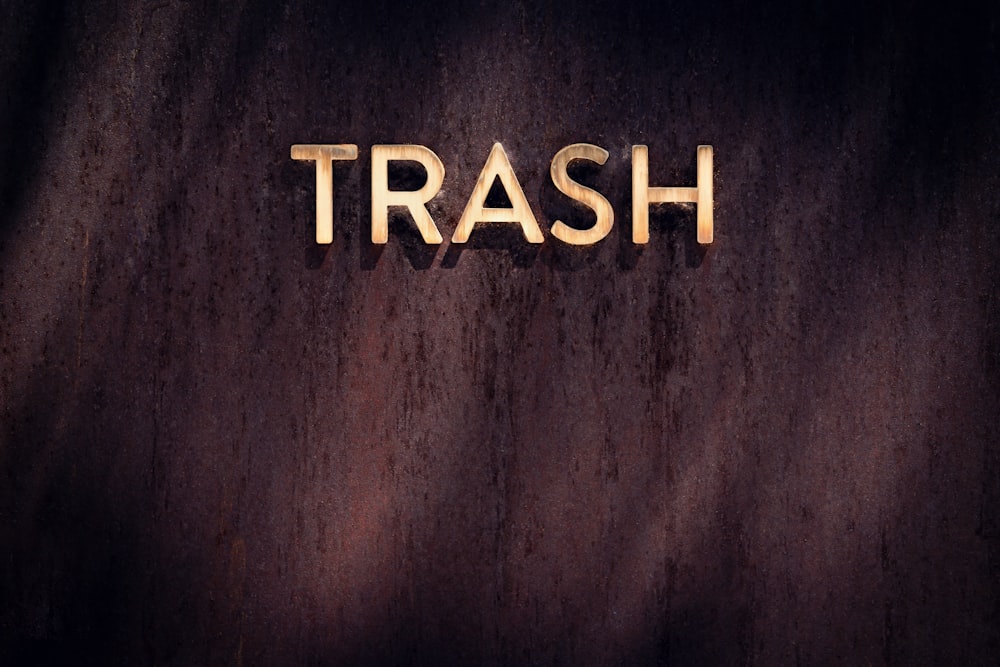 the word trash spelled with gold letters on a dark background
