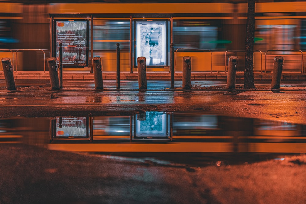 a bus stop with a reflection of the bus