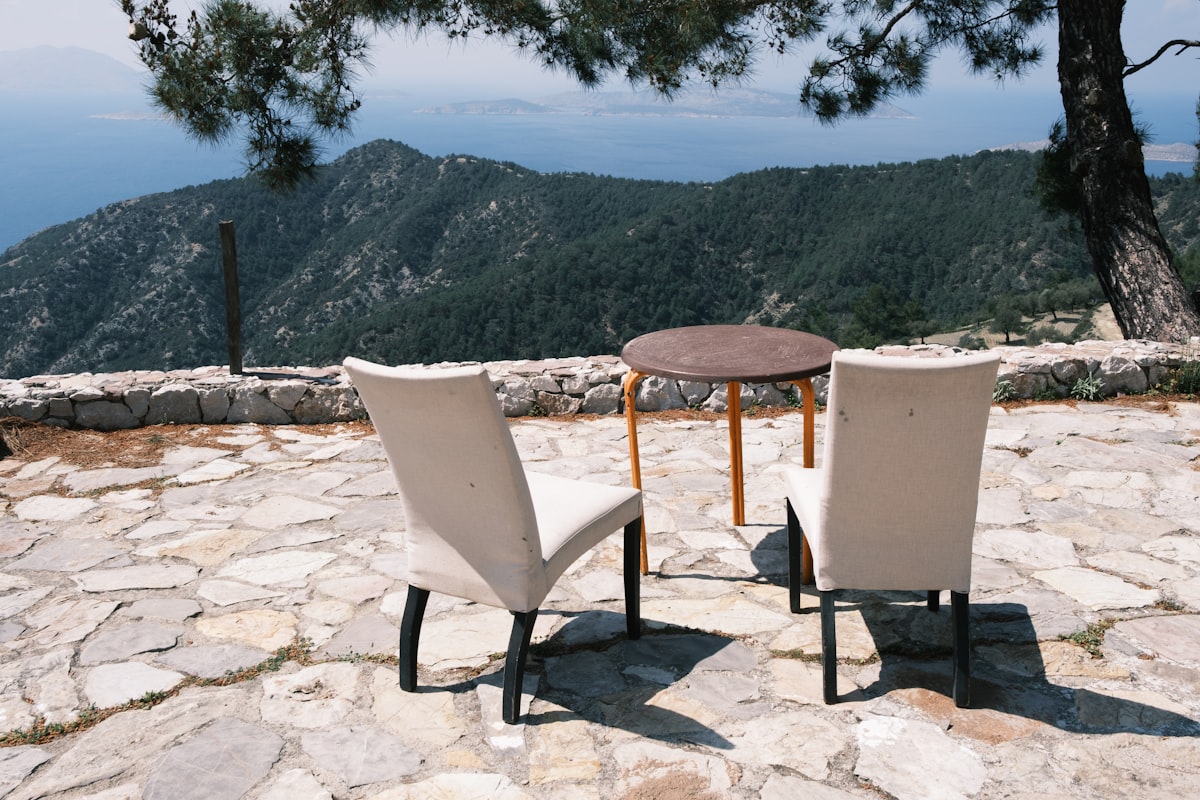 Two chairs and a table arranged on a natural stone patio with scenic view
