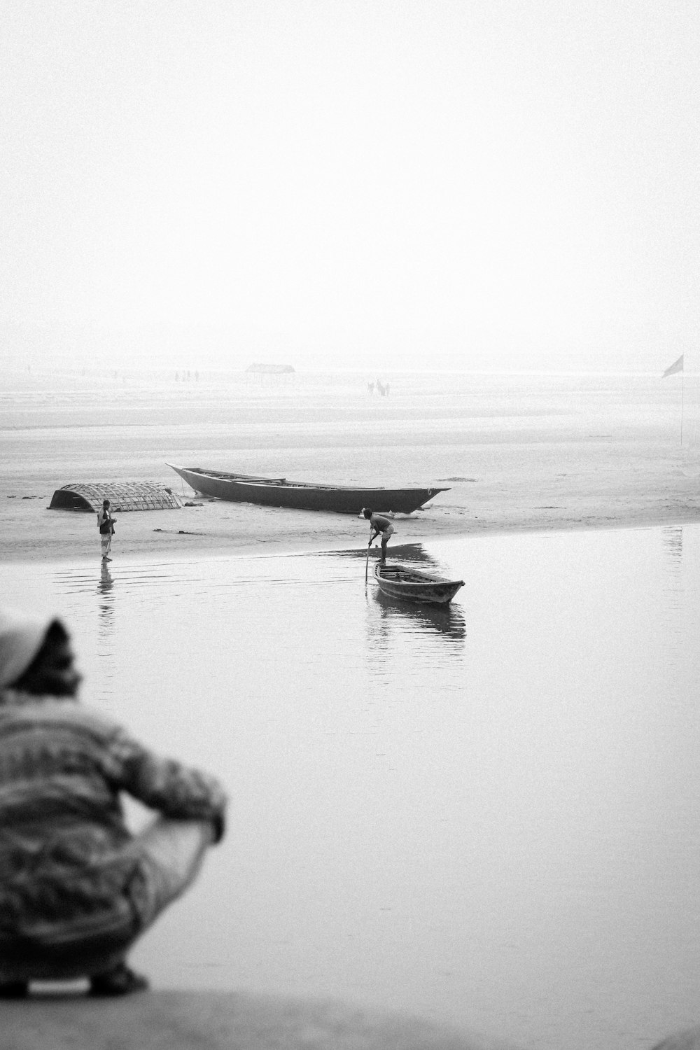 Una foto en blanco y negro de una persona sentada en una playa