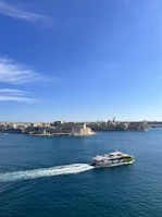 A ferry cutting through sparkling blue waves under a bright, clear sky.