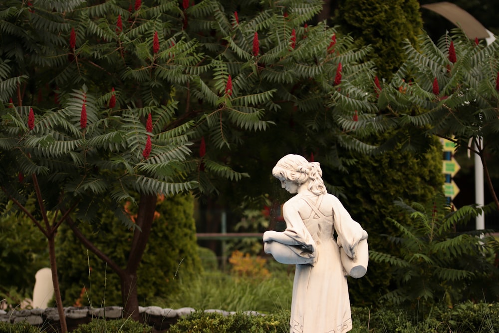 Una estatua de una mujer sosteniendo un pájaro en un jardín