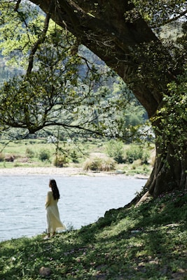 A serene outdoor scene showing a woman wearing a simple, timeless white t-shirt with the bronze diamond logo.