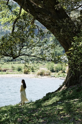 A serene scene of a woman meditating by turquoise water under a soft morning light.
