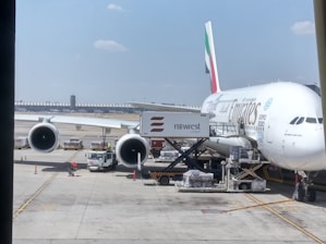 A cargo plane being loaded with packages at an airport under a clear sky.