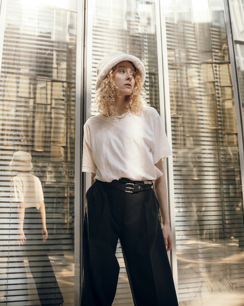 a woman standing in front of a window with a hat on