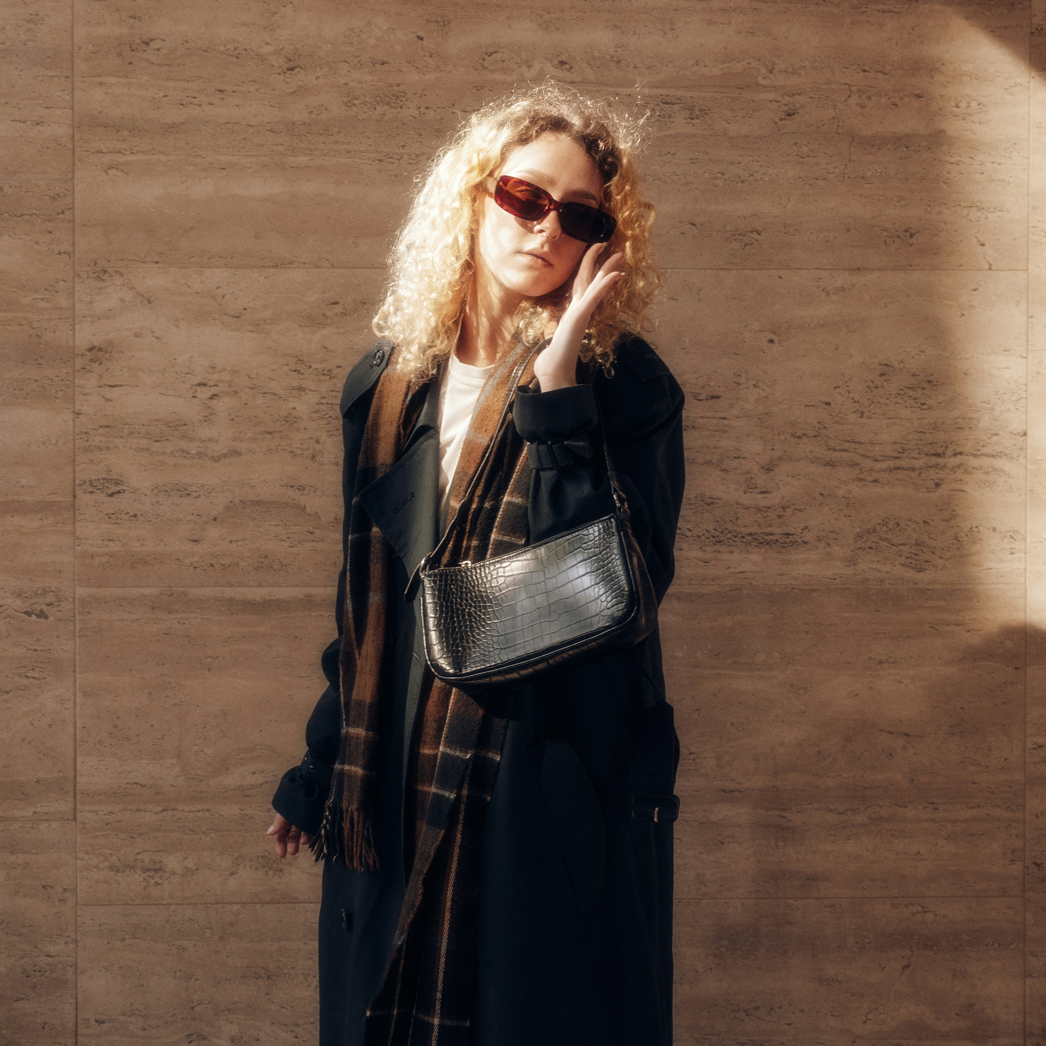 a woman with blonde hair and sunglasses holding a purse